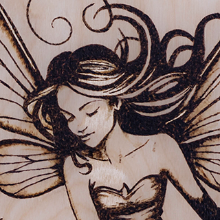 A detailed macro crop of an A4 pyrography piece featuring a delicate fairy with intricate wing detailing.